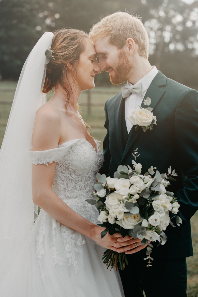 Mains entrelacées de mariés avec bouquet de fleurs blanches, séance photo mariage