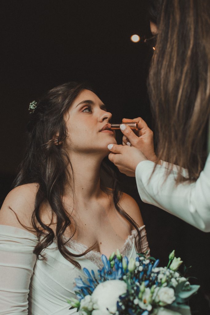 Mariée se remettant du rouge à lèvres sous le regard complice du marié, moment intime de mariage