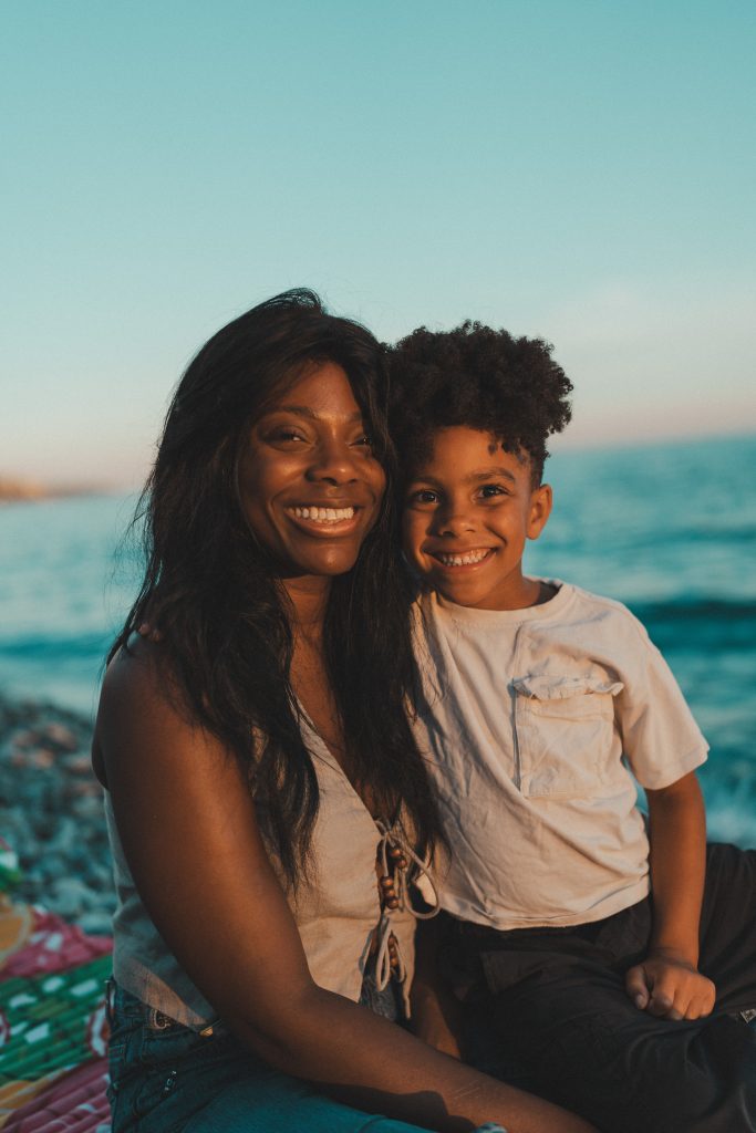 Mère et enfant souriants ensemble face à l'objectif au bord de la mer, séance photo de famille