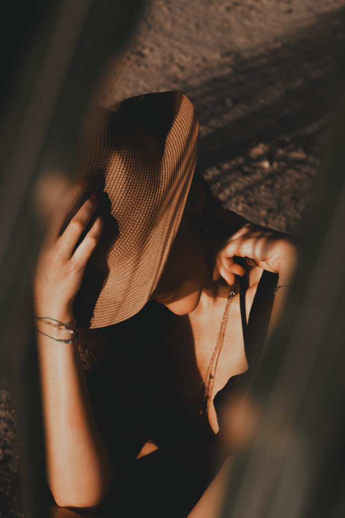 Gros plan de mains tenant un chapeau de paille, détail bohème lors d'une séance photo estivale