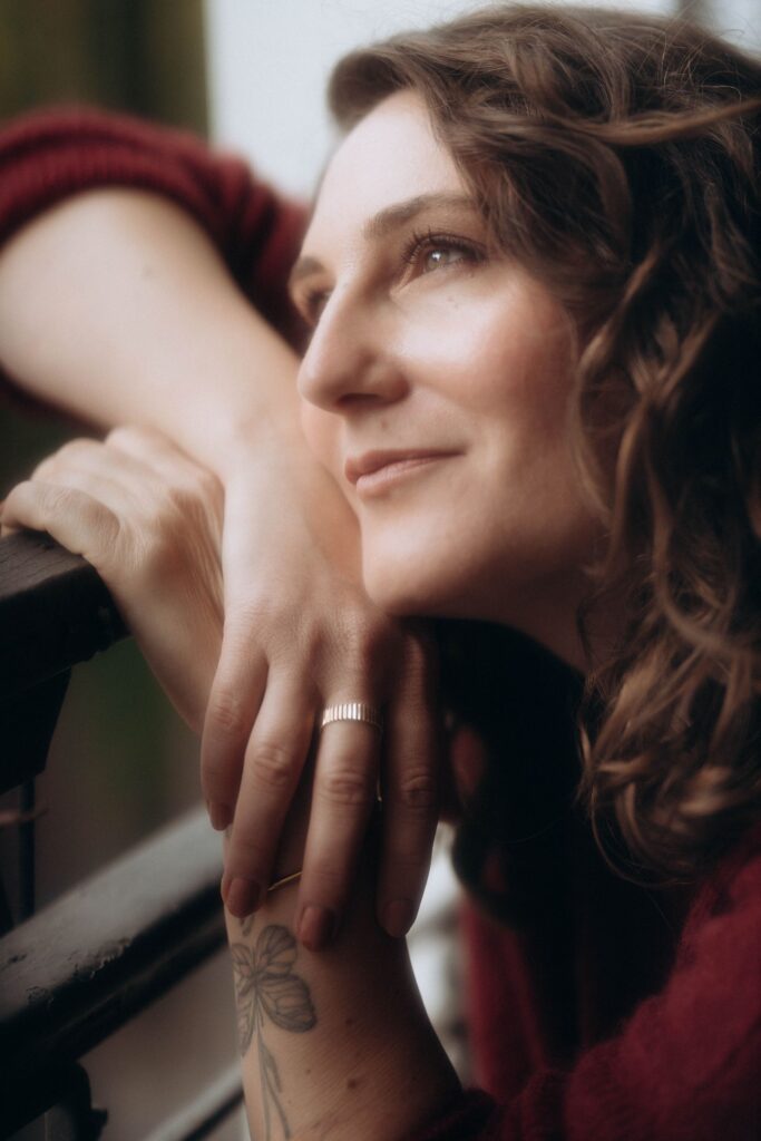 Gros plan artistique de main et visage de femme aux cheveux bouclés, portrait intimiste